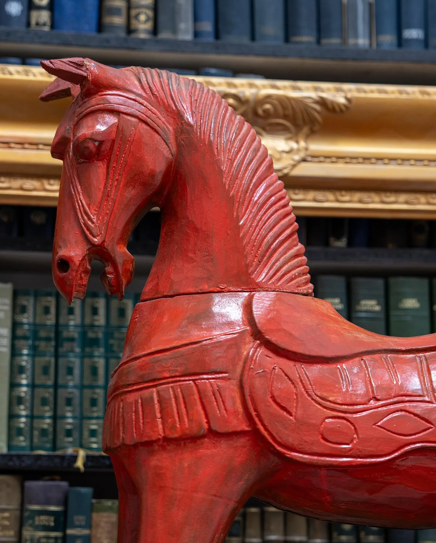 Le cheval de bois rouge, devant les reliures