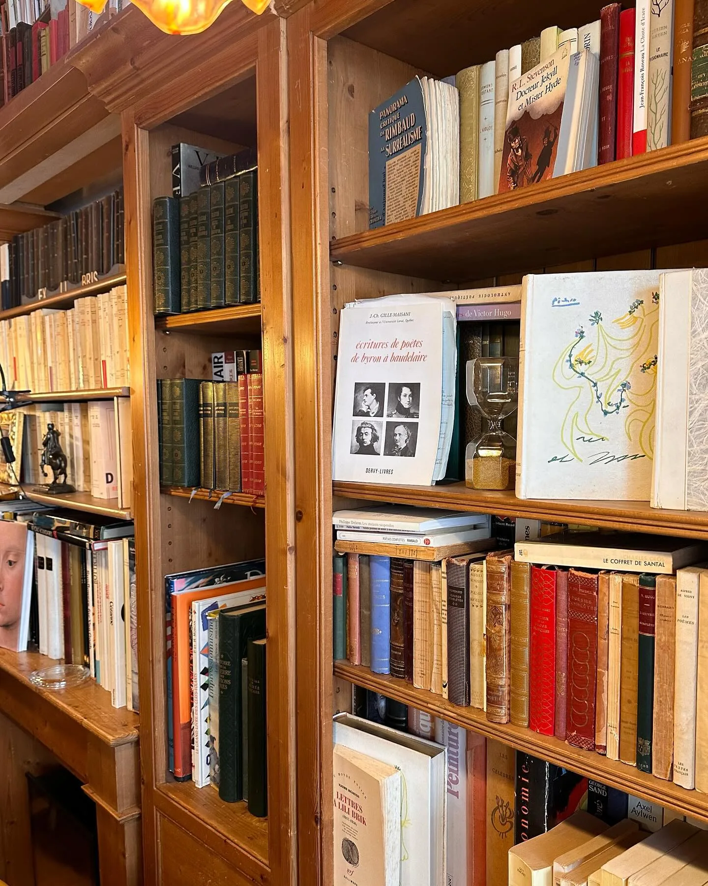 Grande bibliothèque en bois blond chargée de vieux volumes