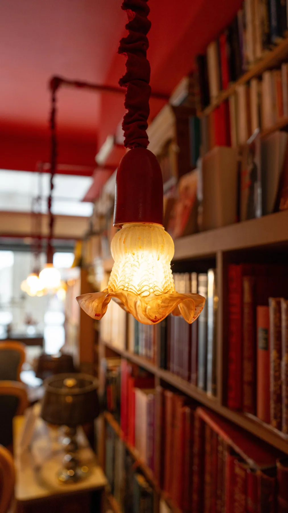 Suspension en verre sous le plafond rouge, devant les livres