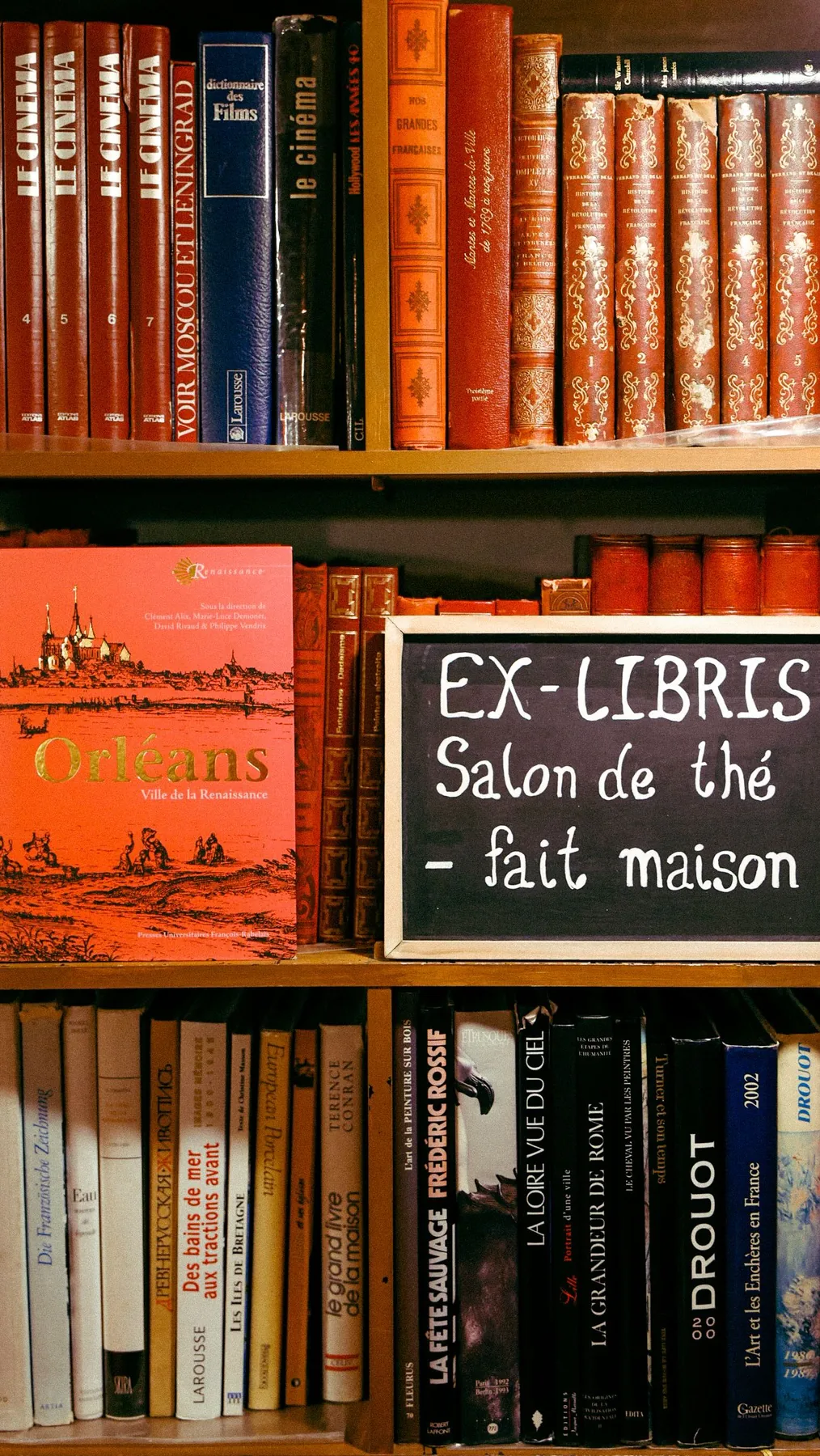 Petite ardoise « Ex-Libris, salon de thé fait maison » posée sur les étagères