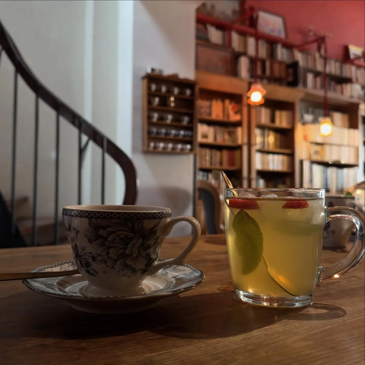 Un thé chaud en tasse bleue et un thé glacé, l’escalier en colimaçon derrière
